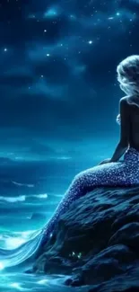 A mermaid sits by the ocean under the night sky.