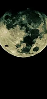 A full moon with a UFO silhouette in the dark night sky.