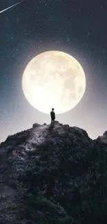 Silhouette on mountain peak under full moonlight and starry night sky.