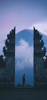 Silhouetted gateway with mountain backdrop in blue misty morning light.