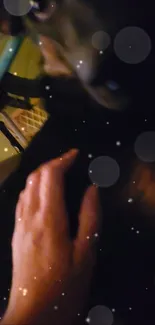 Hand near a figure under a star-filled night sky with glowing dots.