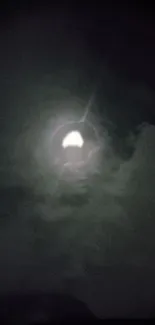 Glowing full moon in dark cloudy sky.