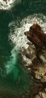 Emerald ocean waves crash against rocky coastline in nature wallpaper.