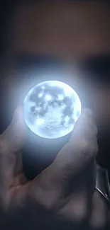 Hand holding a glowing mystical orb in the dark.