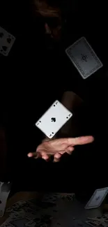 Floating playing cards against dark background with extended hand.