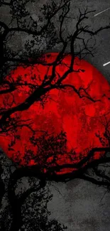 Mystical red moon with silhouetted branches on dark sky.