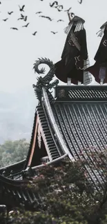 Silhouetted figures on a roof with birds and misty mountains.