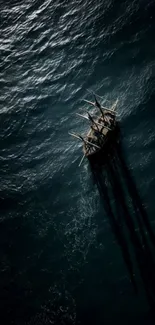 Aerial view of a sailing ship casting shadows on the dark, wavy ocean.