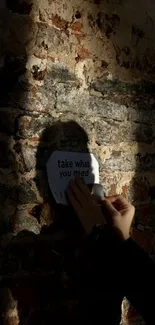 Silhouette and shadow on a brick wall with hand placing a note.