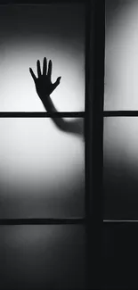 Silhouette of a hand on softly lit panels in monochrome design.