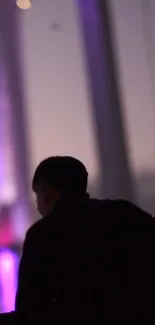 Silhouette on a bridge at sunset in purple hues.