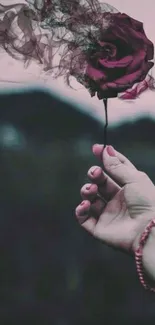 Hand holding a mystical smokey rose on a dark background.