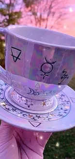 Mystical teacup with cosmic symbols at sunset.