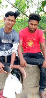 Friends sitting outdoors with greenery in the background.