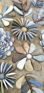 Intricate pebble flowers arranged on sandy background with artistic flair.