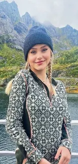 Woman in patterned outfit by lake with mountain view.