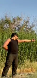 Person pointing towards tall green reeds under a clear sky.