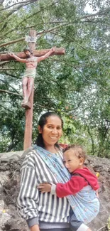 Mother with child in nature, under a crucifix.