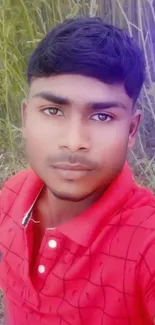 A young man in a red shirt in a natural outdoor setting.