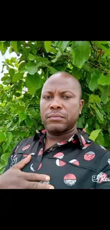 Portrait of a man in front of lush green leaves.