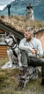 Man and dog by a cabin with mountain views.