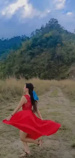 Woman twirling in red dress with hills backdrop.