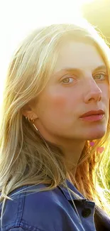 Blonde woman in denim, bathed in golden sunlight, standing in a scenic outdoor setting.