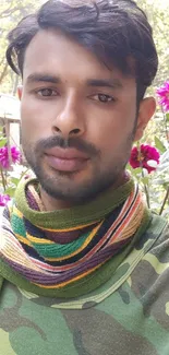 Man in garden with vibrant pink flowers and camo outfit.