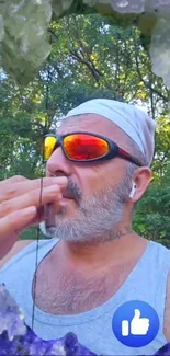 Man in sunglasses with crystals and nature background.