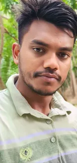 Young man in green outdoor setting, nature-inspired wallpaper.