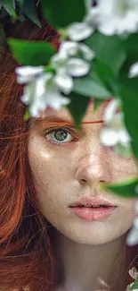 Portrait of red-haired woman surrounded by green leaves and white flowers.