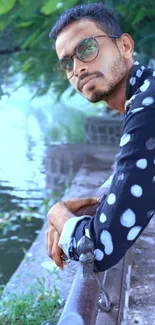 Man in polka-dot shirt by a tranquil lakeside.