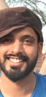 Smiling man in brown cap surrounded by trees.