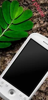 Sleek white phone on textured surface with green leaf.