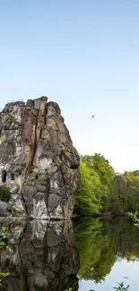 Nature rock reflection wallpaper with clear sky and greenery.