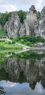 Towering rocks reflecting in a calm lake amid lush greenery.