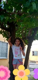 Girl posing under tree with colorful flowers, peace sign, outdoor scene.