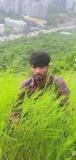 Man sitting in tall green grass with cityscape background.