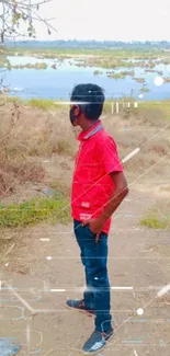 Person in red shirt by riverside with blue sky backdrop.