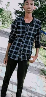 Young man walking on a green path with trees and grass.