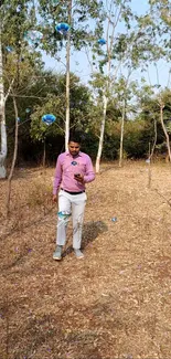 Man walking in forest with floating bubbles, creating a whimsical scene.