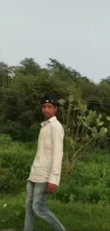 Person walking amidst lush green landscape with trees.