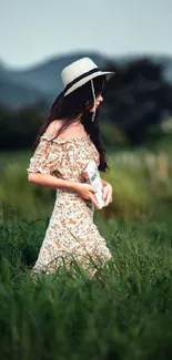 Woman in floral dress and hat walking in a lush green meadow.