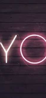 Neon 'YOU' text glowing on dark wood background.