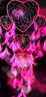 Neon pink heart-shaped dream catcher on black background.