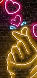 Neon hand and heart art on a dark brick background.