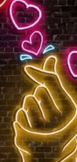 Neon illuminated heart and hand gesture art on a dark brick wall.