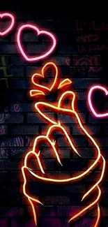 Neon heart gesture on dark brick wall with vibrant colors.