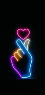 Neon hand showing heart gesture on black background.