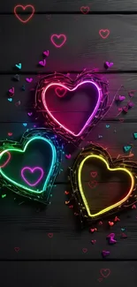 Colorful neon heart shapes on black wood background.